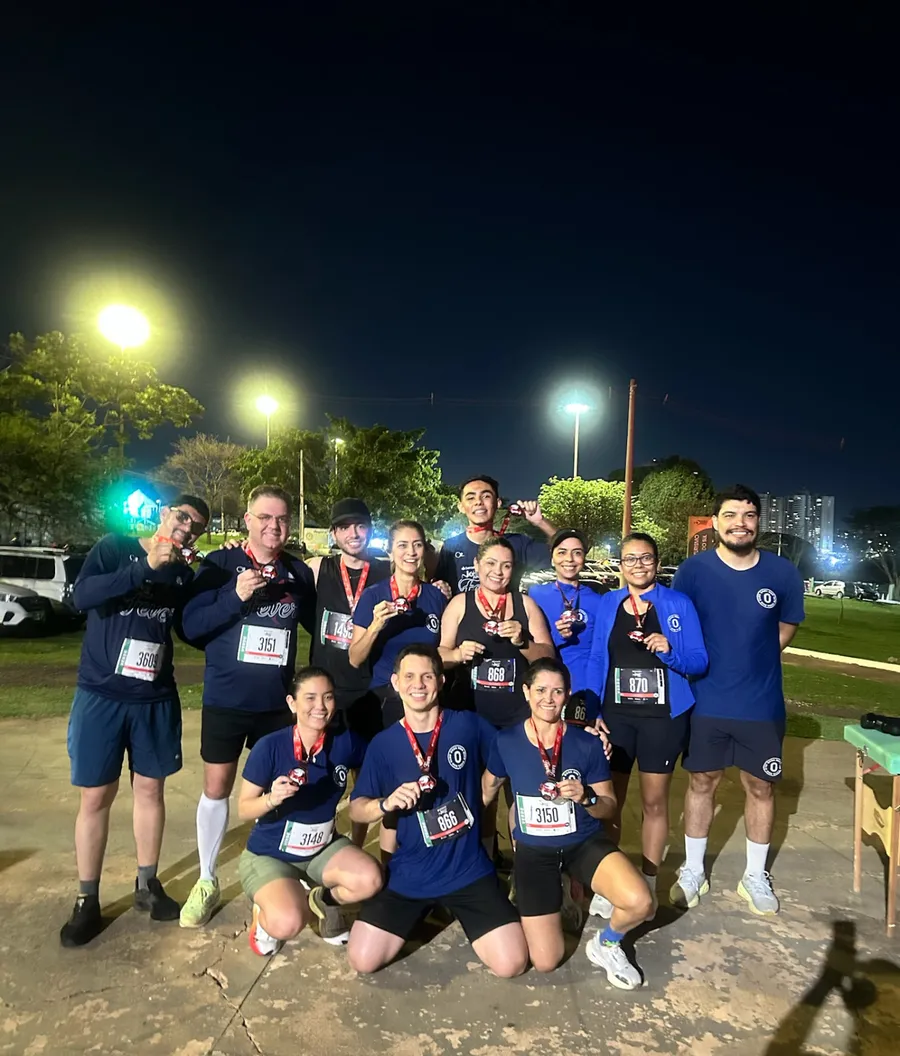 Atletas do Onda Run Club comemorando com medalhas após prova noturna